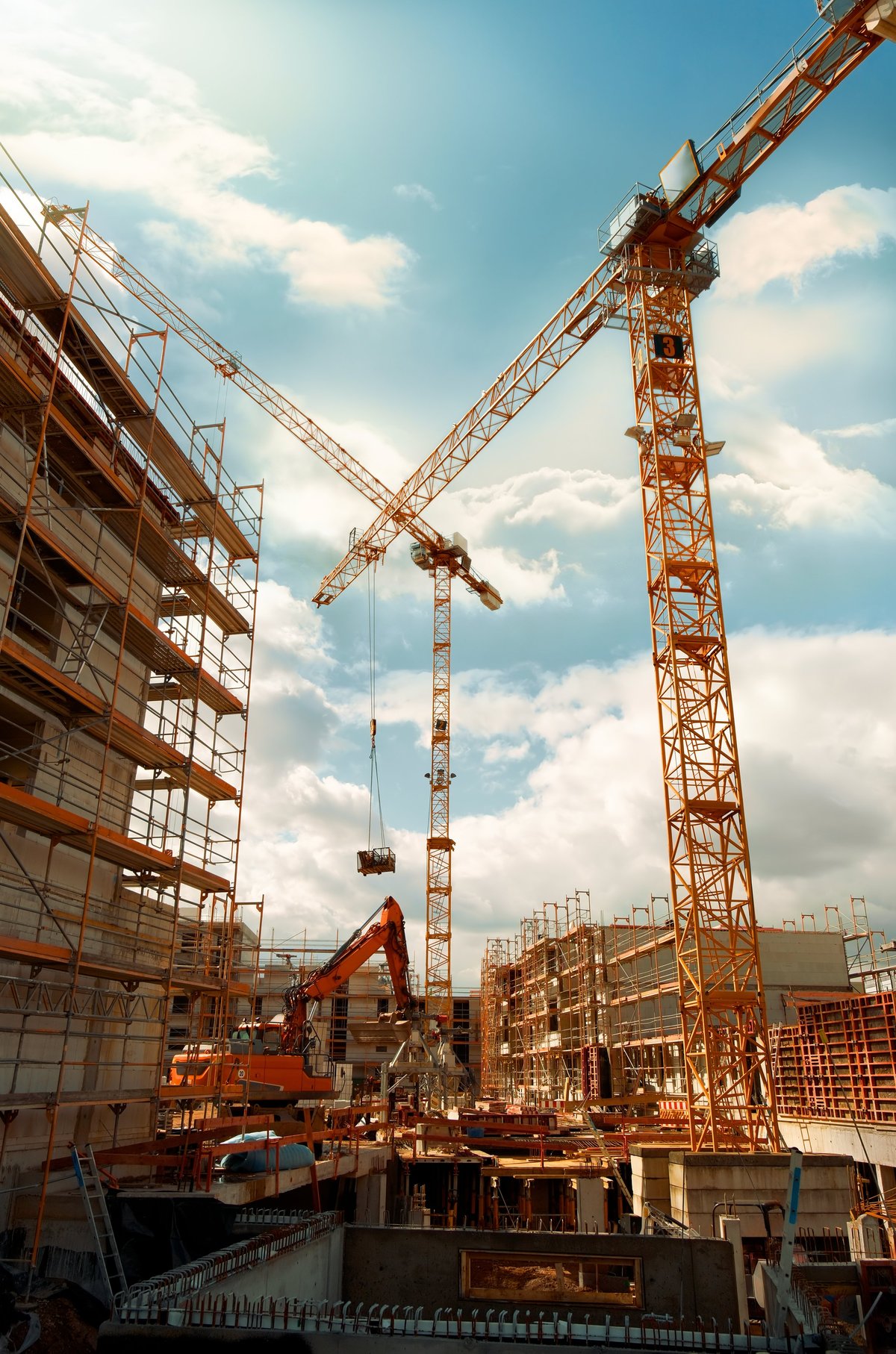 Construction site with cranes against dramatic sky